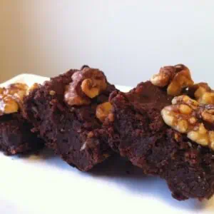 3 brownies with walnuts on top on a white plate