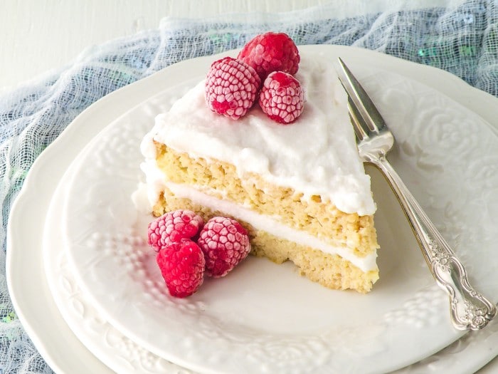 Vanilla Coconut Flour Cake topped with raspberries on a white plate