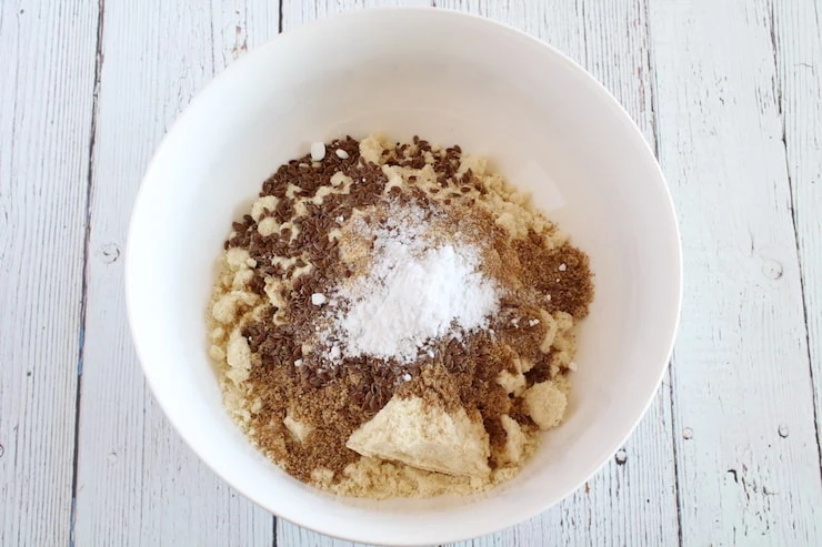 Unmixed dry keto bread recipe ingredients in white bowl on white wooden table