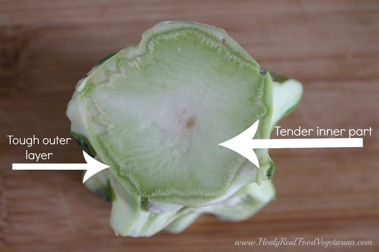 A close up of a broccoli stalk with arrows pointing out the outer layer and inner part