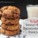 A pile of almond flour chocoalte chip cookies on a work surface with a glass of milk