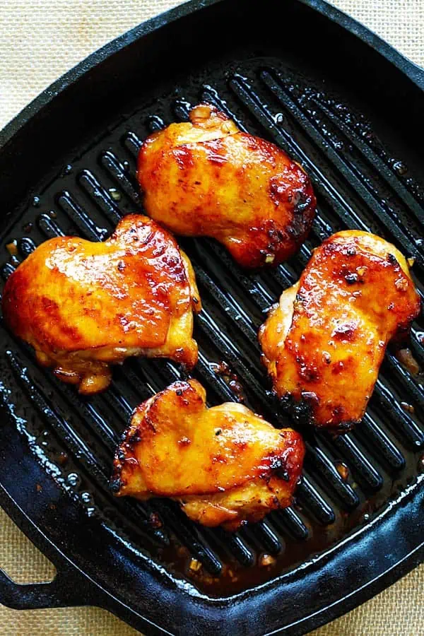 Cast iron pan with orange hued turmeric chicken thighs in it