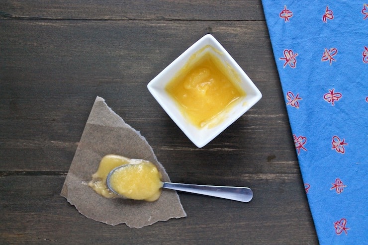 white cup with yellow ghee in it next to spoonful of ghee