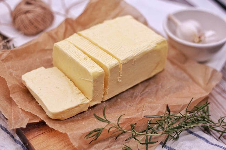 Stick of butter on brown wax paper next to rosemary