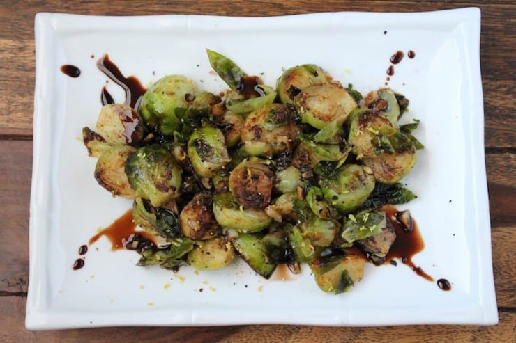 brussels sprouts on a white plate with balsamic glaze drizzled over it