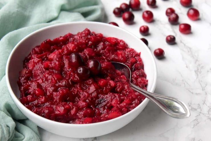 A small white bowl of homemade cranberry sauce on a marble surface