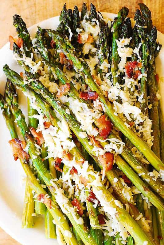 A close up of roasted asparagus with bacon and cheese