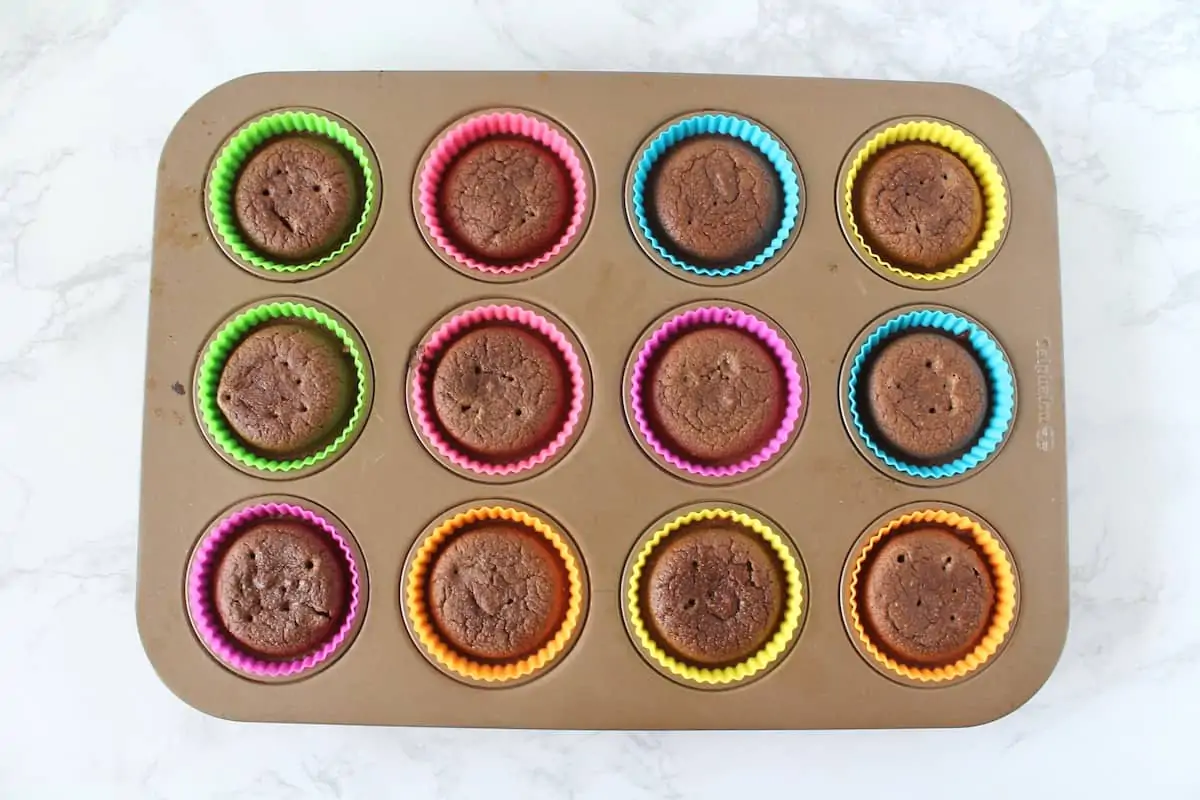 Overhead shot of muffin tin filled with baked chocolate muffins in muffin liners