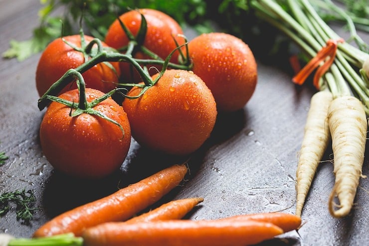 Water flecked tomatoes and carrots on a wooden surface