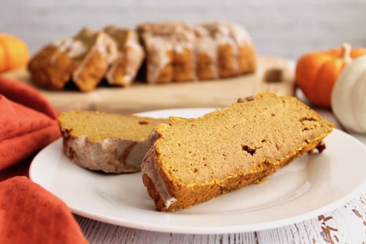 Close up up slices of healthy paleo pumpkin bread on a white plate with loaf in the background