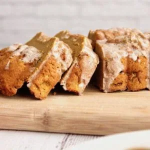 Closeup side view of sliced loaf of healthy paleo pumpkin bread with white icing on top
