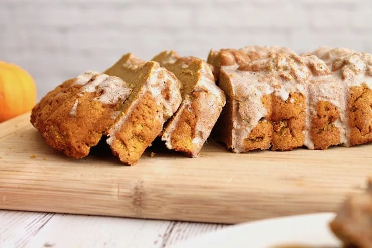 Closeup side view of sliced loaf of healthy paleo pumpkin bread with white icing on top