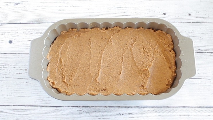 Uncooked paleo pumpkin batter in loaf pan on white wooden surface