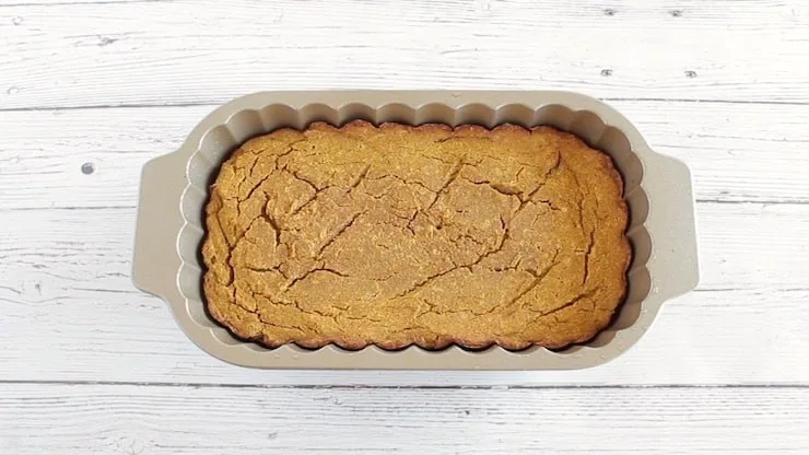 Baked paleo pumpkin batter in loaf pan on white wooden surface