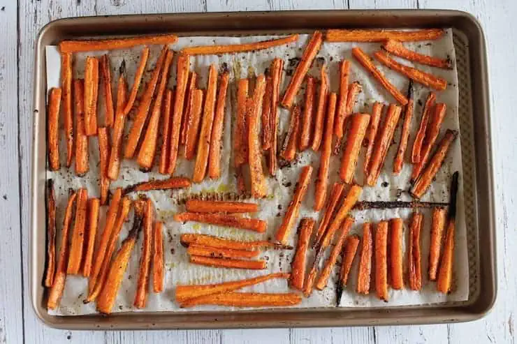 overhead view of baked carrot fries on a baking sheet lined with parchment paper