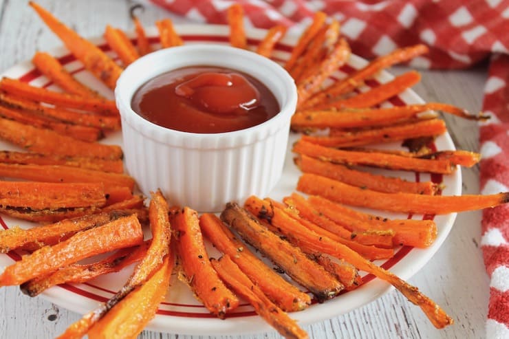 Plate with carrot fries arranged in a circle around a white ramekin of ketchup