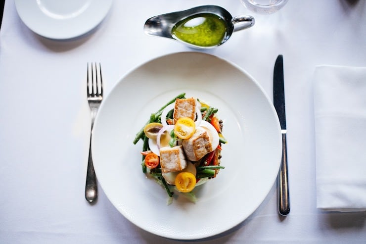 White plate with chicken salad on it on a white table cloth