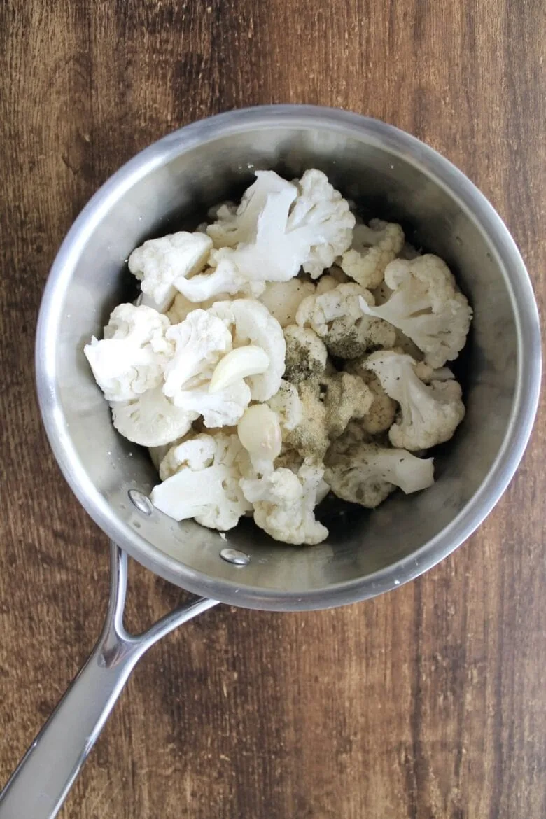 Cauliflower florets in a pot on a wooden table.