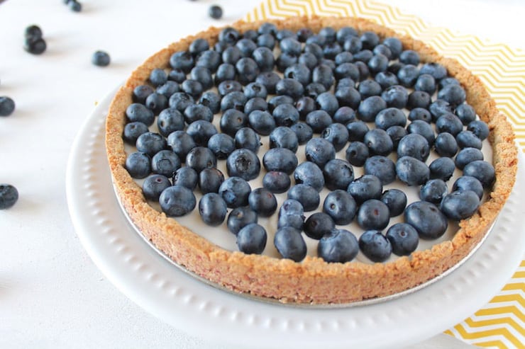 A whole blueberry tart on a white plate