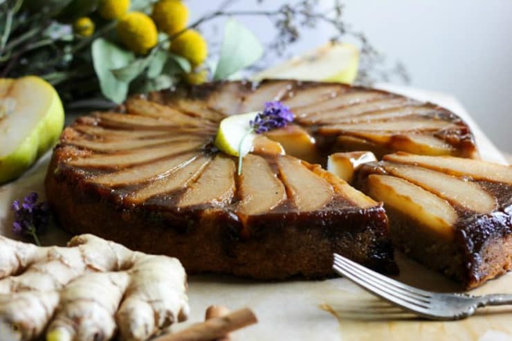 A whole pear upside down cake with a slice cut out