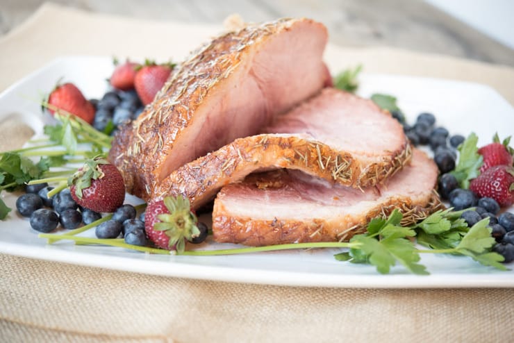 A slow cooked ham on a serving platter cut into slices