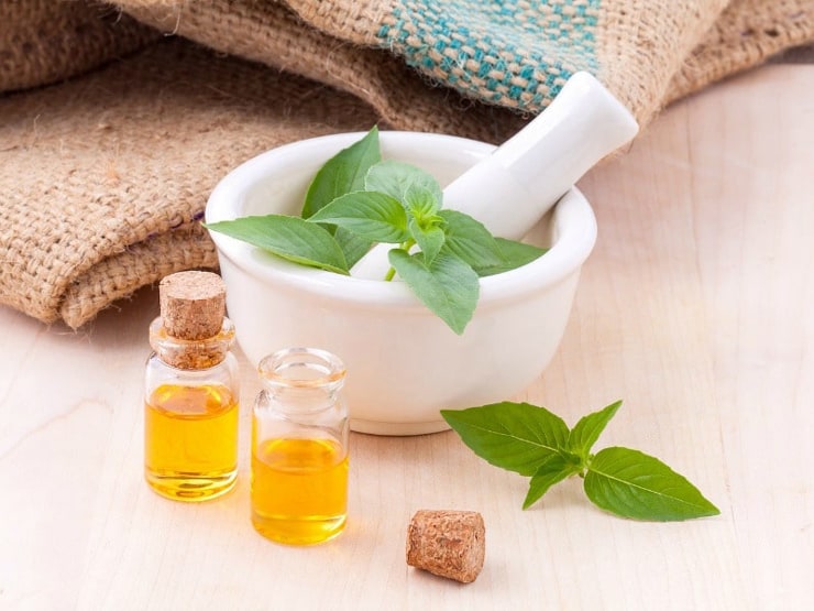 A photo of a mortar and pestle with herbs an essential oils at the side