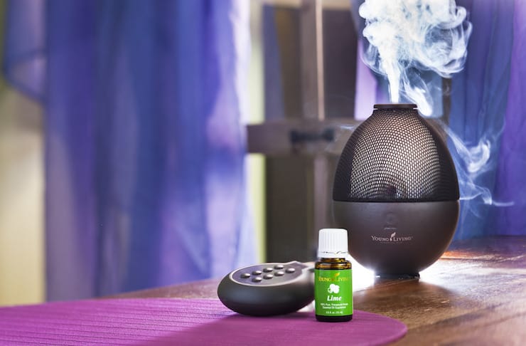 Black essential oil diffuser on wooden table with lime essential oil