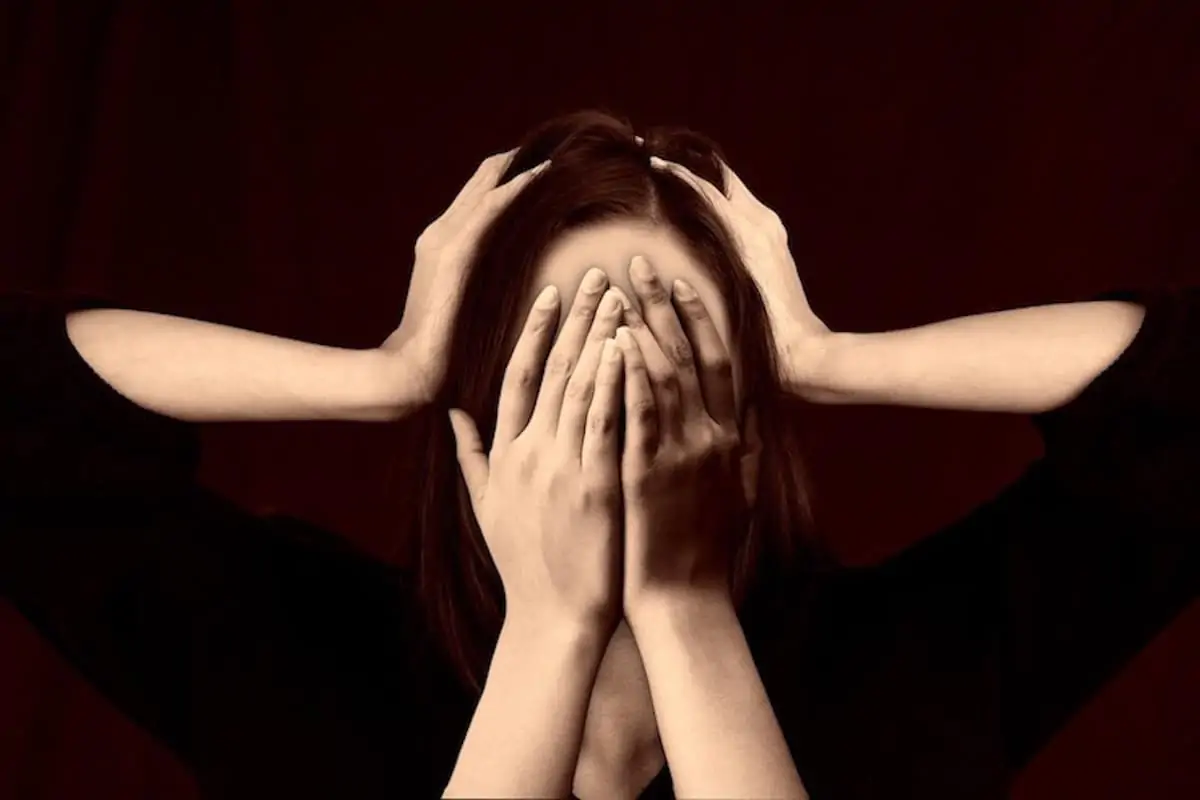 Woman covering her face with her hands with two hands on her head