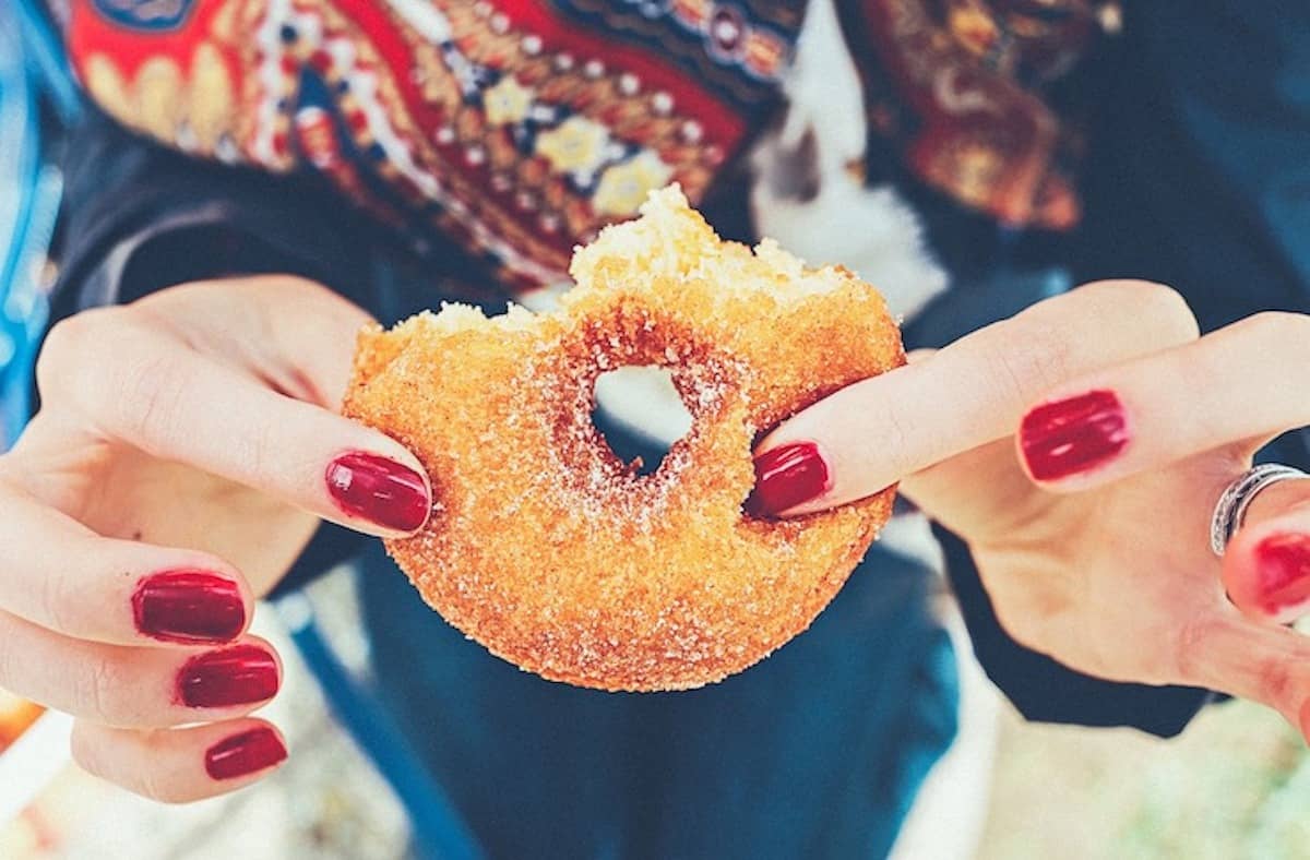 Close up of woman's hands holding a half eaten donut