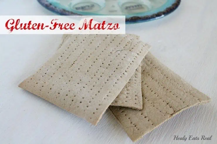 3 sheets of gluten free matzo on a white wooden table next to a clear and blue seder plate