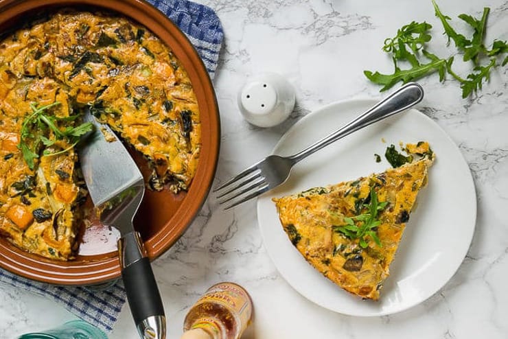 An ovehead shot of an egg bake in a dish with a slice on a plate