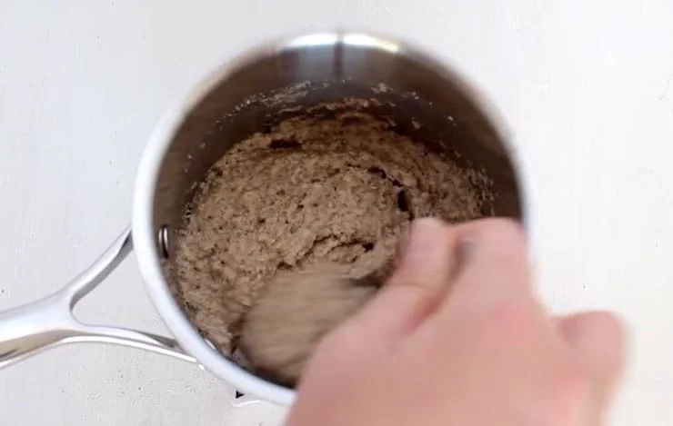 Finished thickened no oats oatmeal in a stainless steel pot on a white wooden table