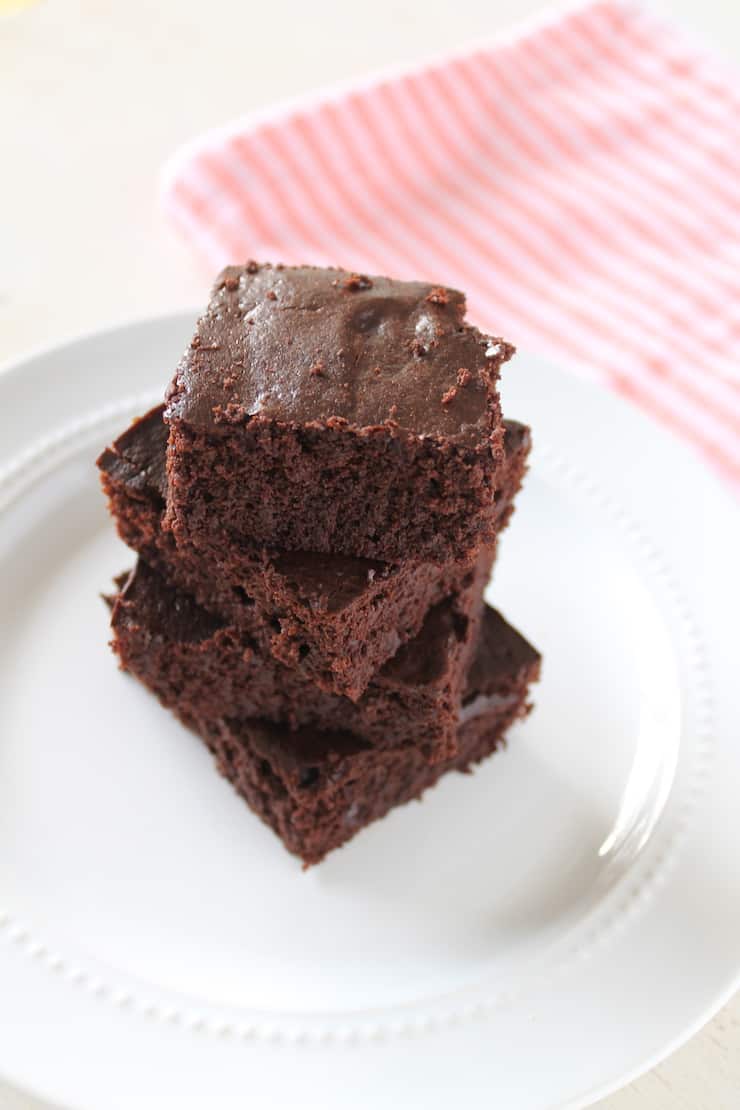 Four stacked flourless brownies on a white plate