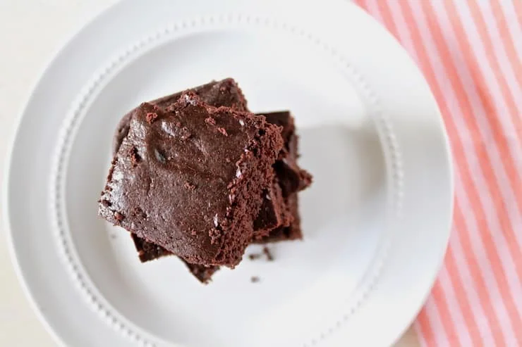 Overhead closeup of stacked flourless brownies on a white plate