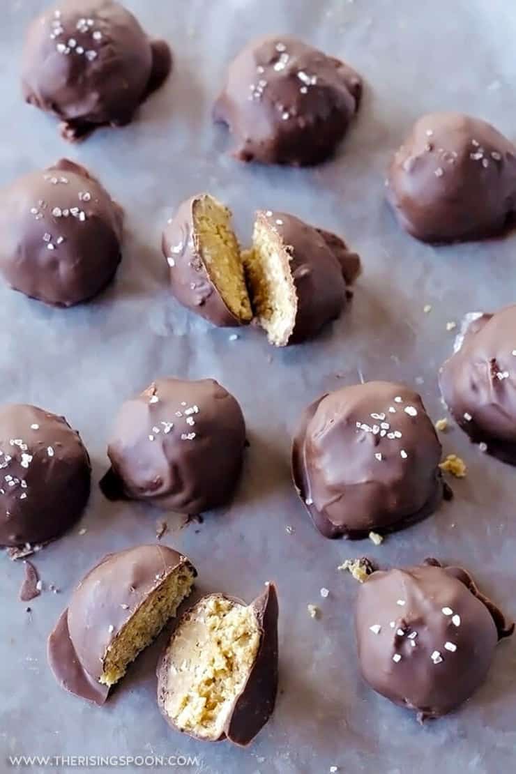 Peanut butter balls dipped in chocolate sitting on a dark surface