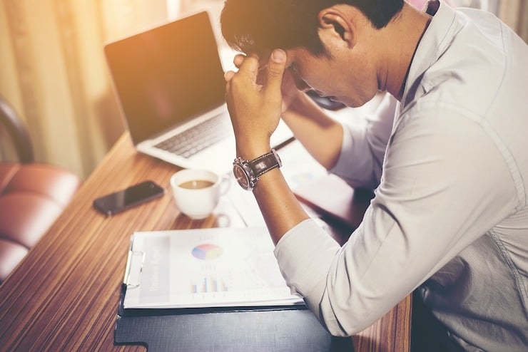 Stressed man at desk with head in hands