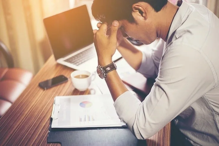 Stressed man at desk with head in hands