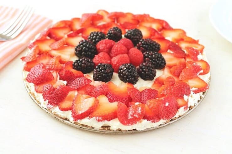 A side shot of a No Bake Fruit Tart sitting on a white surface