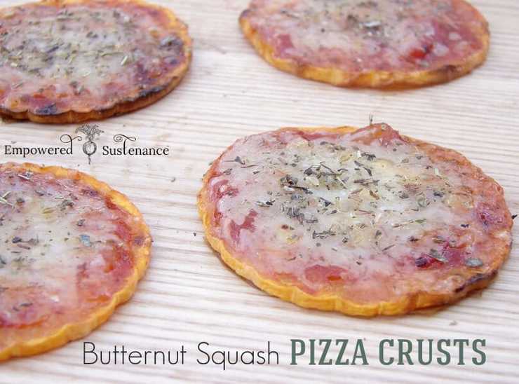 Four healthy pizza crust pizzas made from rounds of butternut squash sitting on a wooden surface