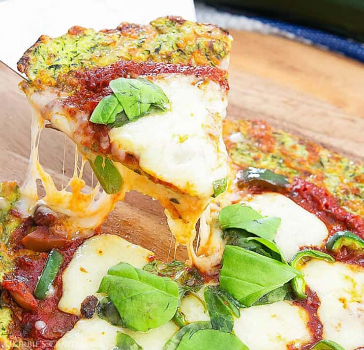 A close up of a slice of healthy pizza with stretchy cheese and basil on the top