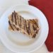 homemade paleo protein bars drizzled with chocolate stacked on a white plate with red napkin next to it on a white wooden table