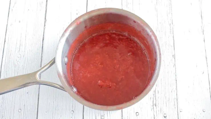 pureed strawberry in stainless steel pot on white wooden surface