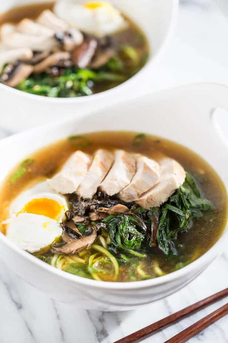 A bowl of chicken ramen with egg, greens and noodles