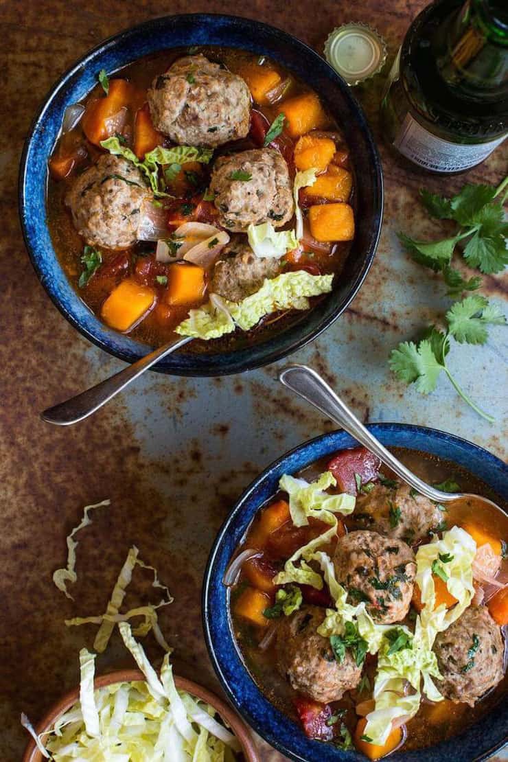 Two bowls of meatballs soup with carrots and other veg
