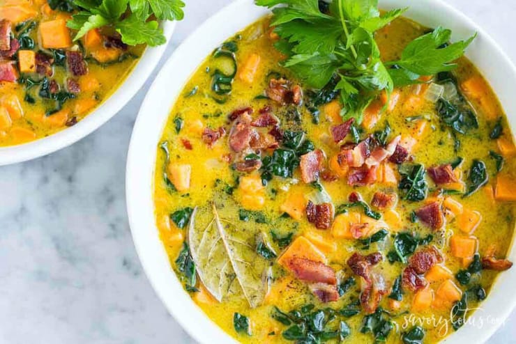 A bowl of sweet potato soup topped with bacon and herbs