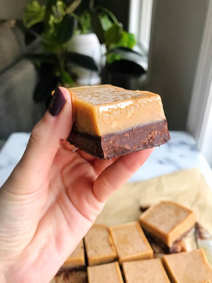 Hand holding a two-layer chocolate and almond butter bar