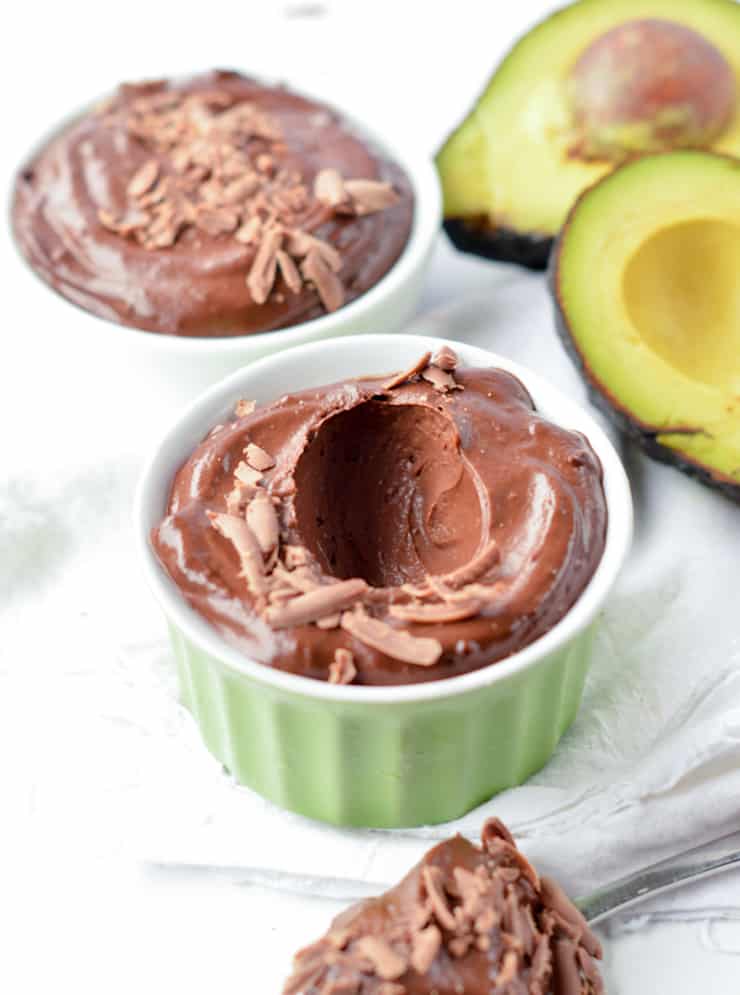 two dishes with chocolate mouse next to halved avocado