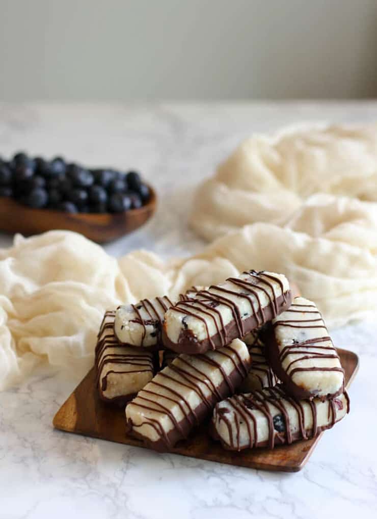 A stack of collagen protein bars drizzled with chocolate on a white surface