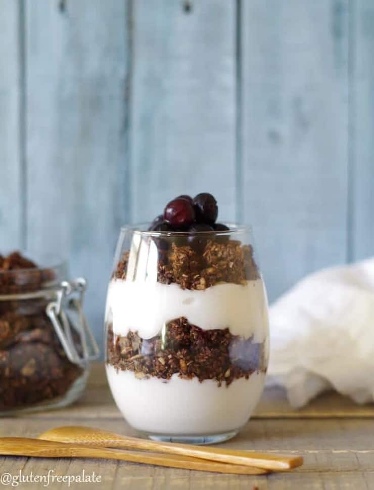 A glass of paleo chocolate granola parfait on a wooden surface