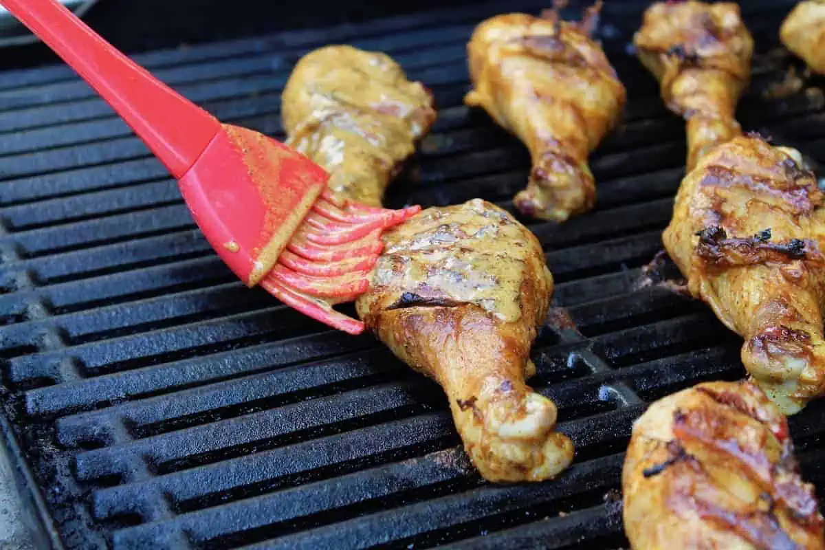 chicken tandoori on a bbq grill being brushed with marinade